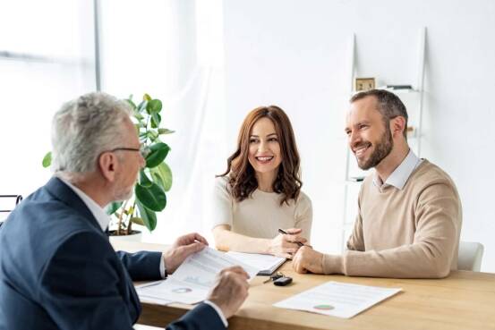 Happy couple at a desk with a salesman